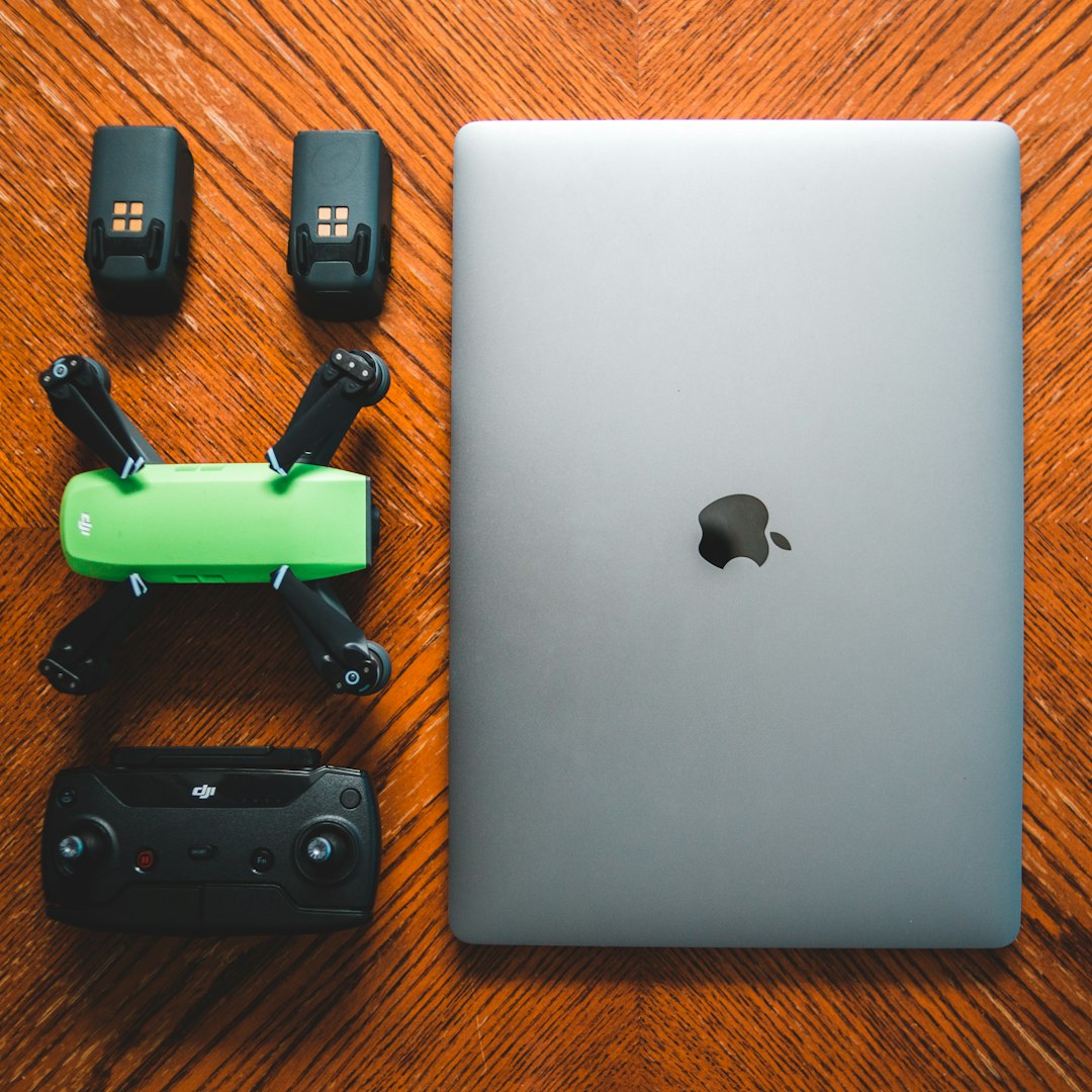 silver macbook beside black and green smartphone case