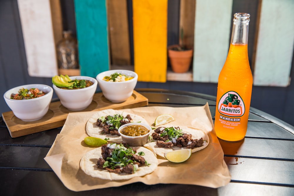 orange juice bottle beside green ceramic bowl with food