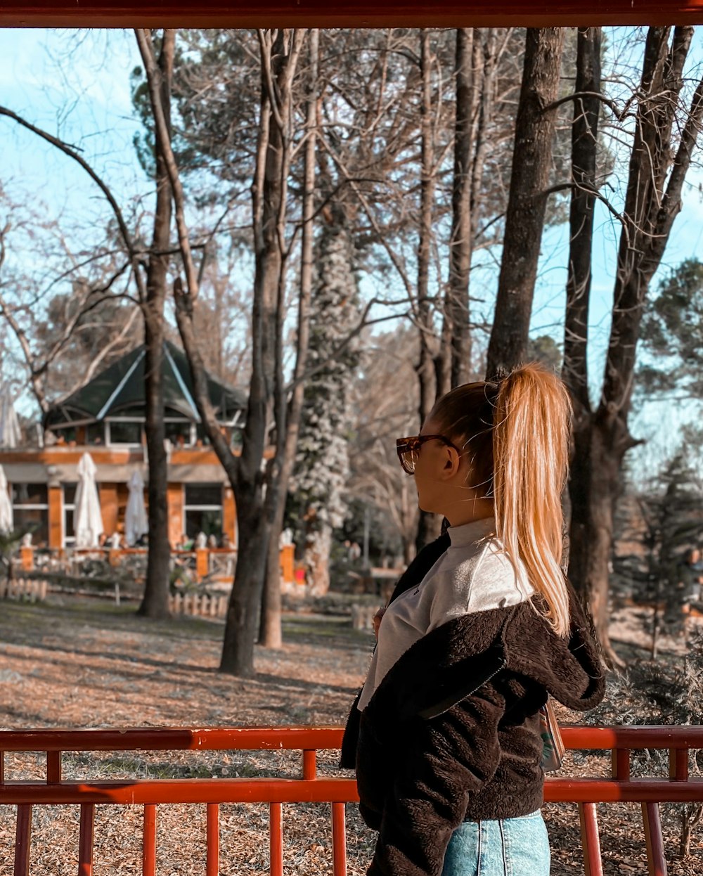 woman in black coat sitting on red bench during daytime