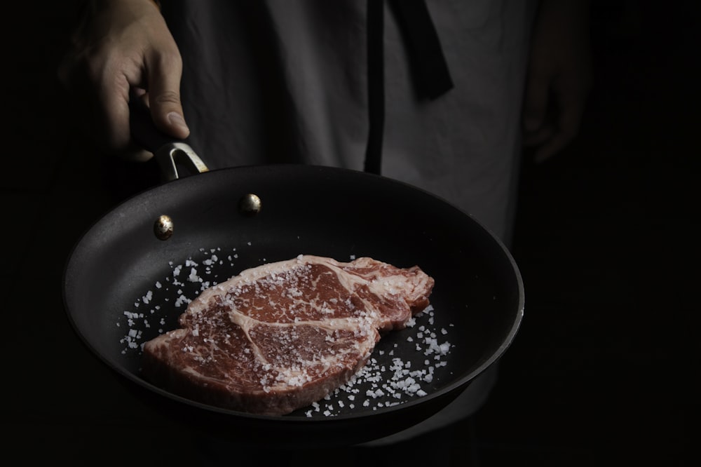 person cooking meat on black pan