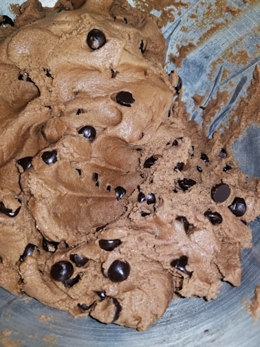 A close-up of a glass bottle filled with layered cookie dough and chocolate chips.