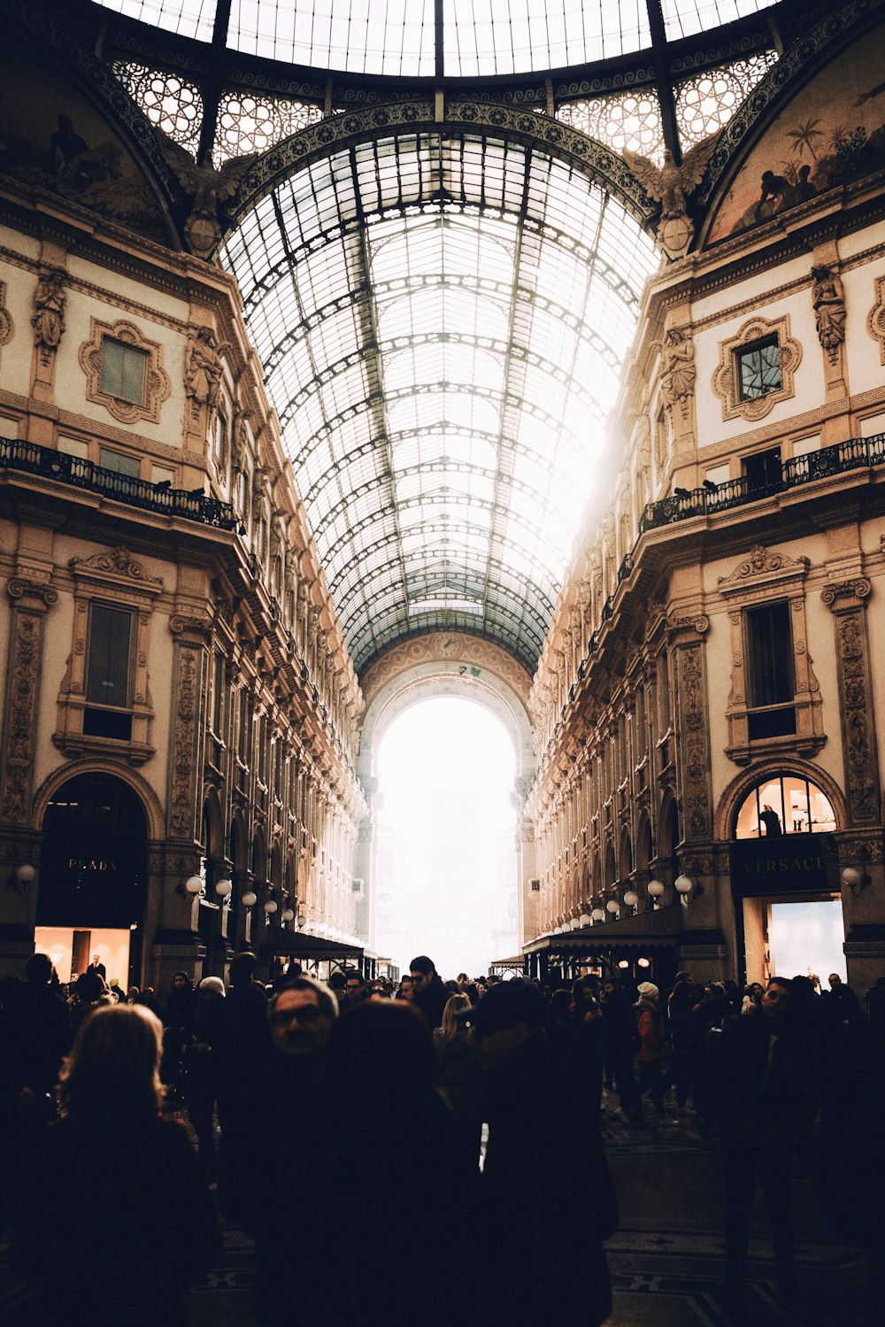 persone che camminano sulla strada in mezzo all'edificio in cemento durante il giorno