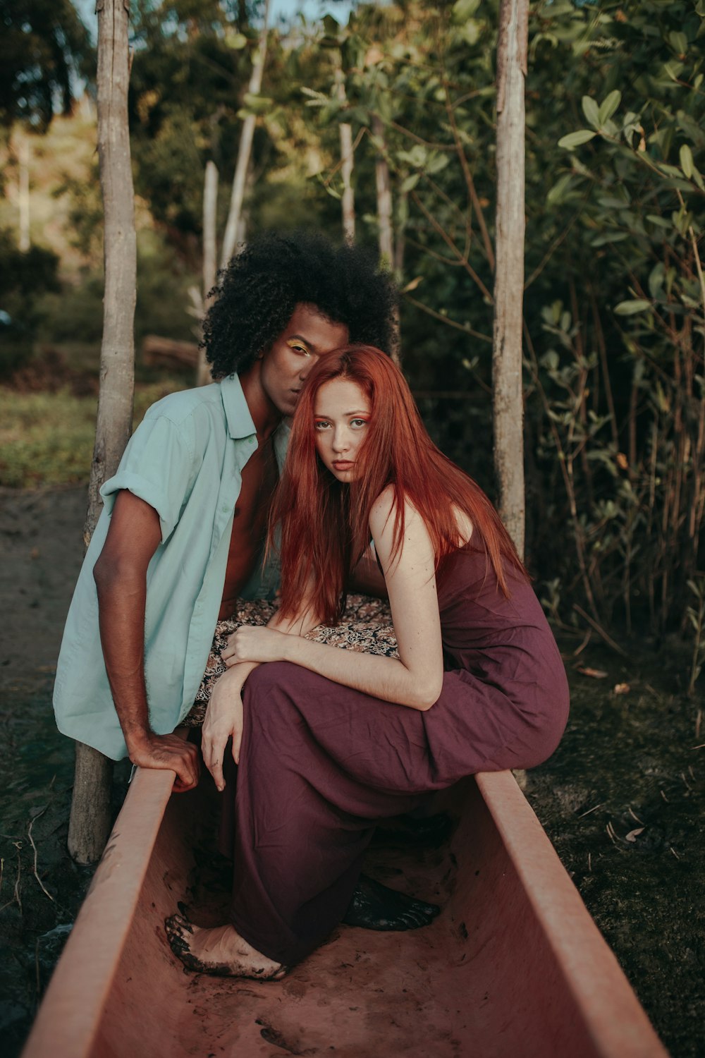 man in white t-shirt and woman in red dress sitting on brown wooden bench