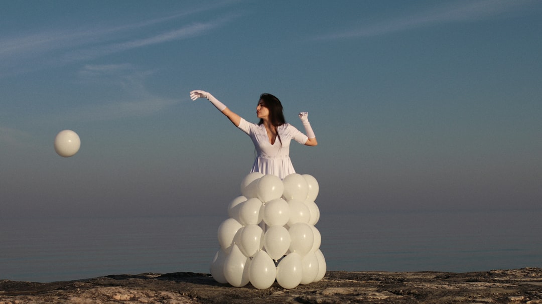 woman in white dress holding white balloons