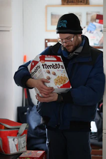 A happy customer unpacking a Serendwave dry fish delivery box in a cozy Canadian kitchen.