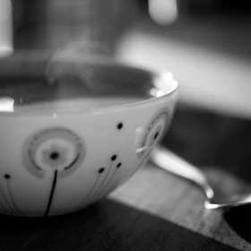 Close-up of a colorful ceramic mug with hand-painted patterns, steam rising gently from the cup.