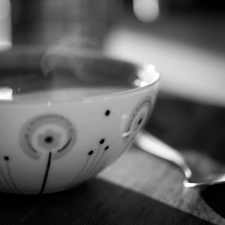 Close-up of a colorful ceramic mug with delicate hand-painted patterns, steam rising from freshly brewed tea.