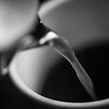 A close-up shot of fresh milk pouring smoothly into a glass container on a dairy farm.