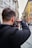 A man photographing a charming small town street filled with colorful buildings.