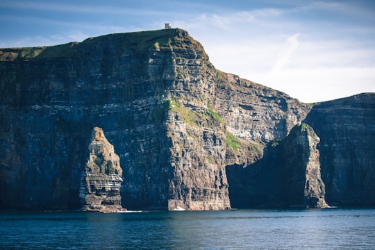 gray and brown rock formation on sea during daytime in Cliffs of Moher Ireland