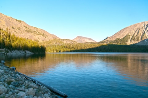 body of water near mountain during daytime