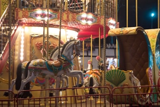 Children laughing and playing on colorful carousel horses under bright lights.