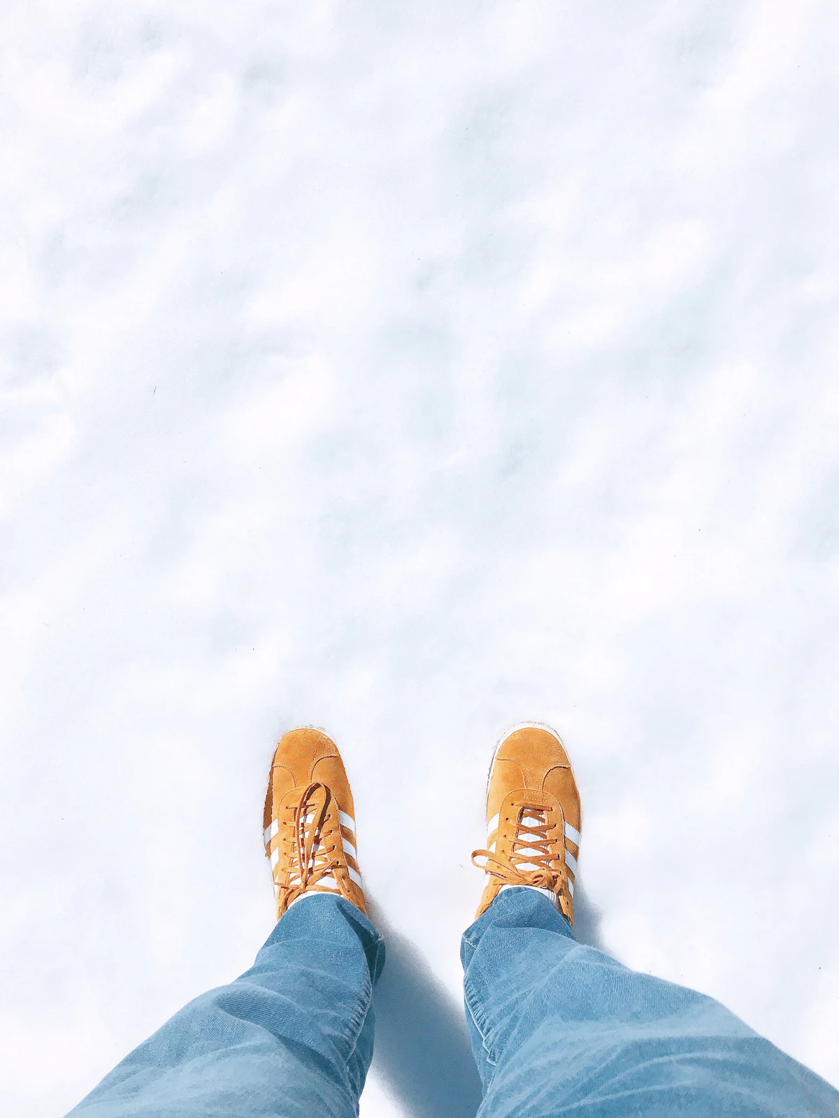 Pernas de homem de calça jeans azul e botas marrons vistas de cima