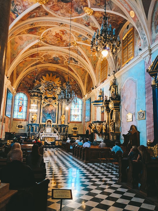 people sitting on chair inside cathedral in Kraków Old Town Poland