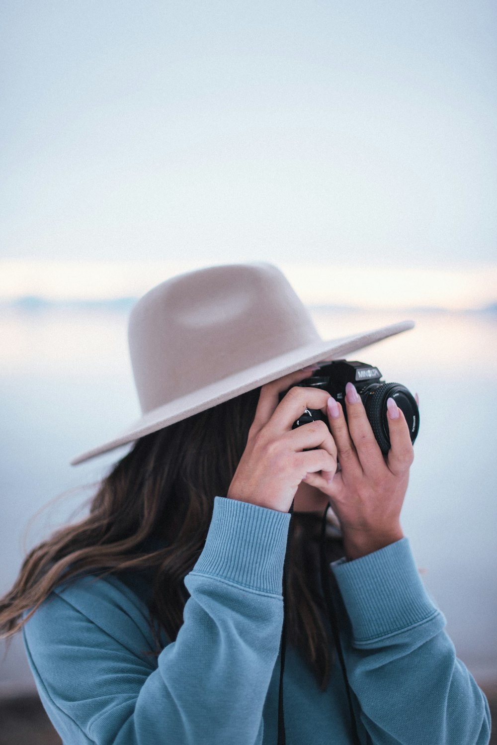 woman in blue sweater wearing beige hat