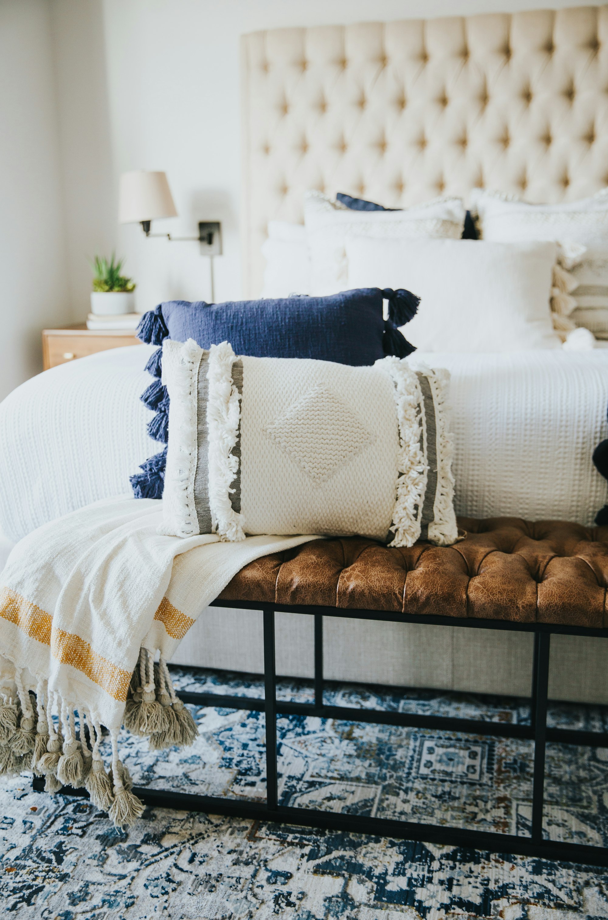 white neutral base bedroom with boho cushions, throws and an area rug