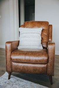 A craftsman carefully upholstering a vintage chair in a warm, minimalist workshop with beige and brown tones.