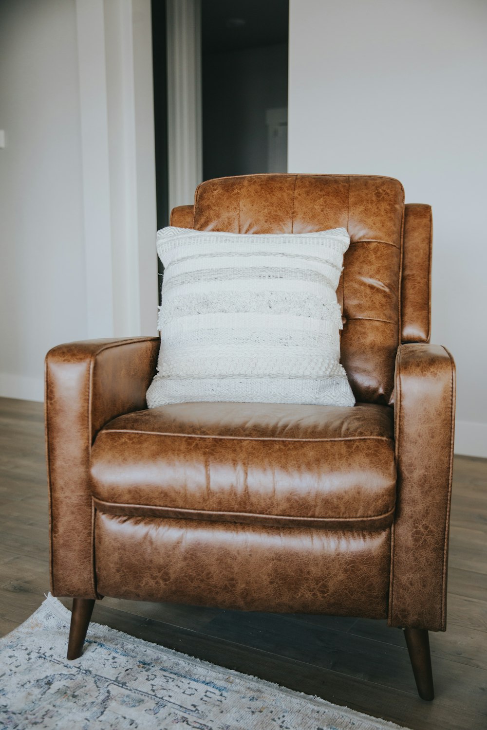 fauteuil en cuir marron avec coussin blanc