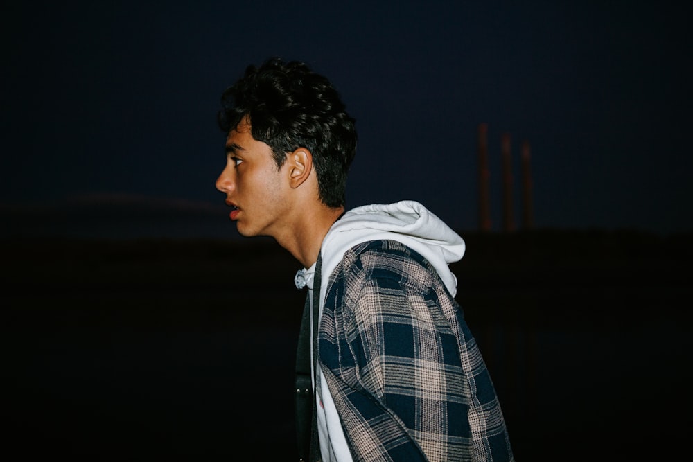 a man with a hoodie on standing in the dark