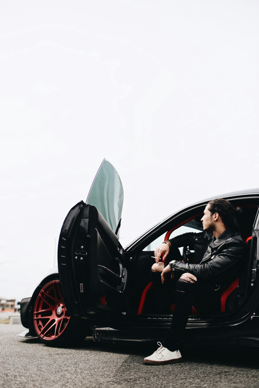 Mann in schwarzer Jacke fährt schwarzes Auto