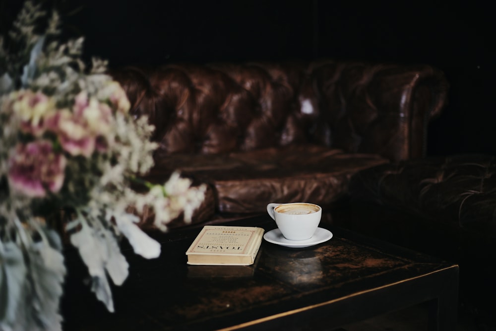 a table with a cup of coffee and a book on it