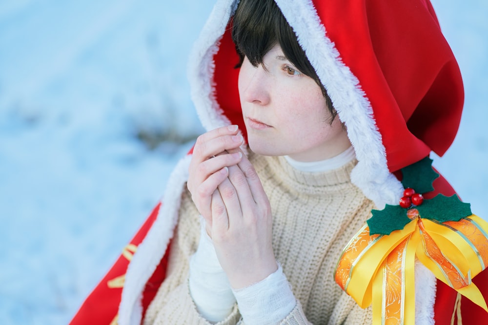 woman in white turtleneck sweater covering her face with red and white textile