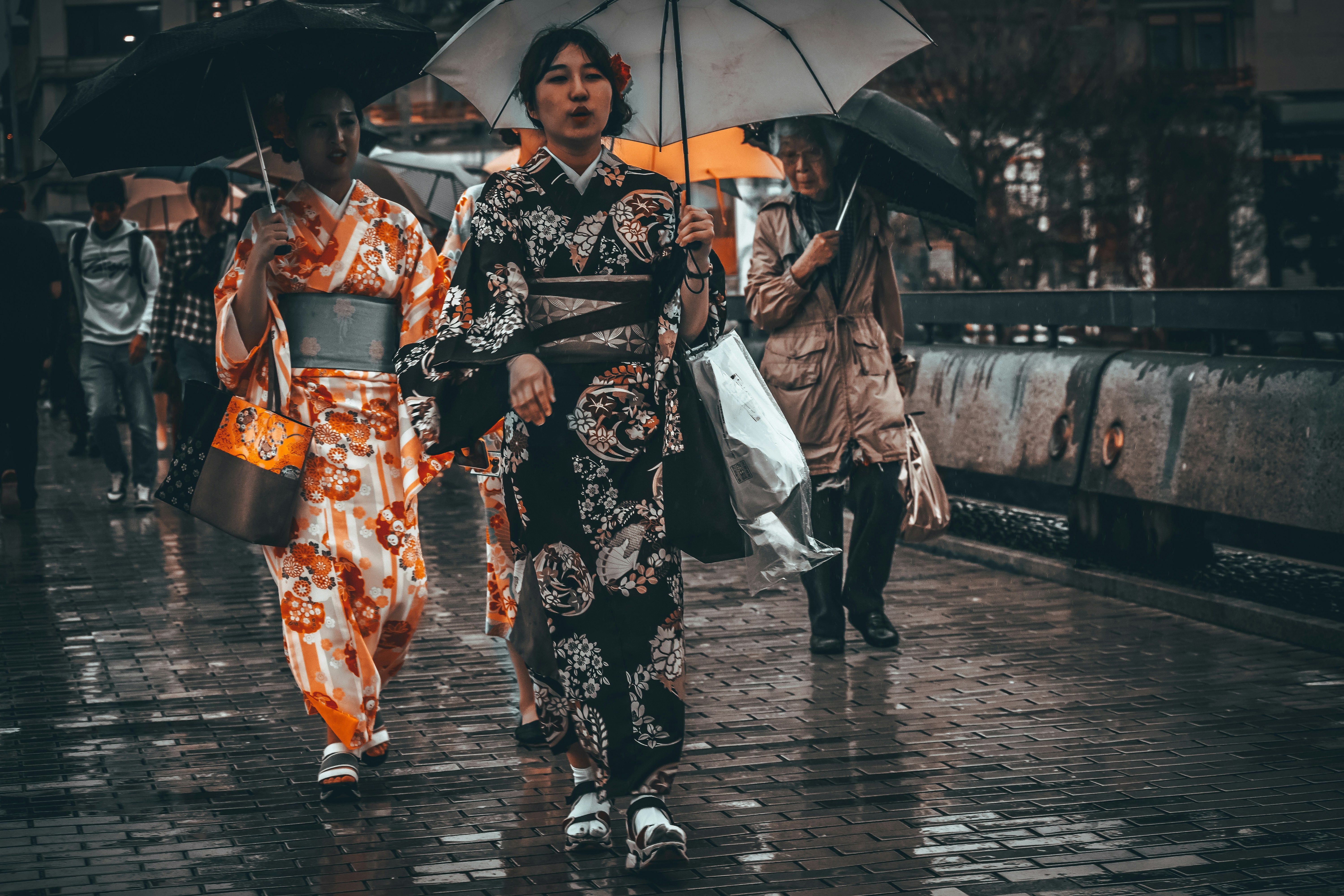 2 women in black and white kimono holding umbrella walking on sidewalk during daytime, 