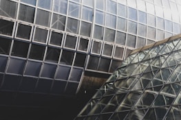 An architectural detail featuring sharp angles and a mix of glass and concrete textures.