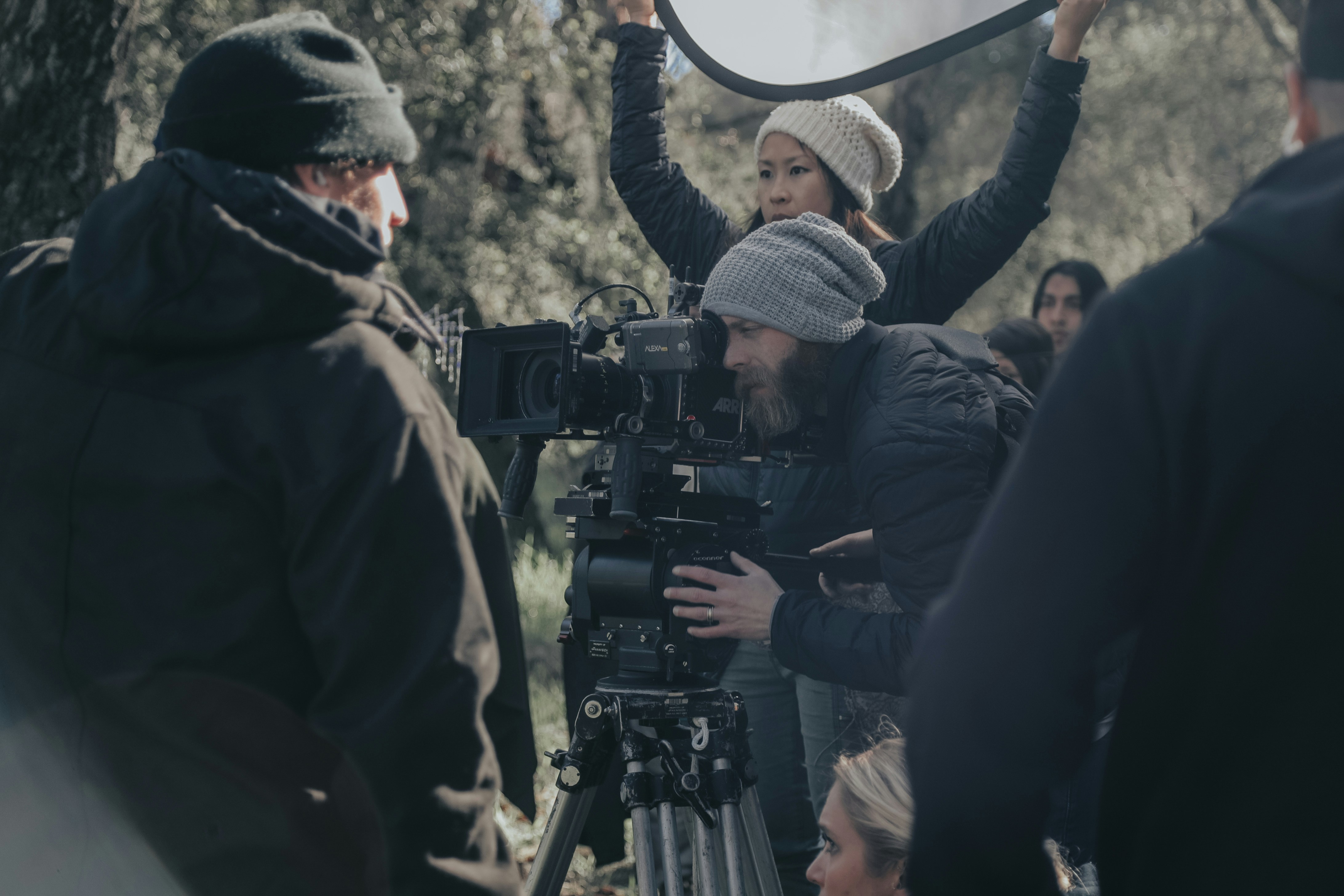 people in black jacket standing in front of camera with tripod