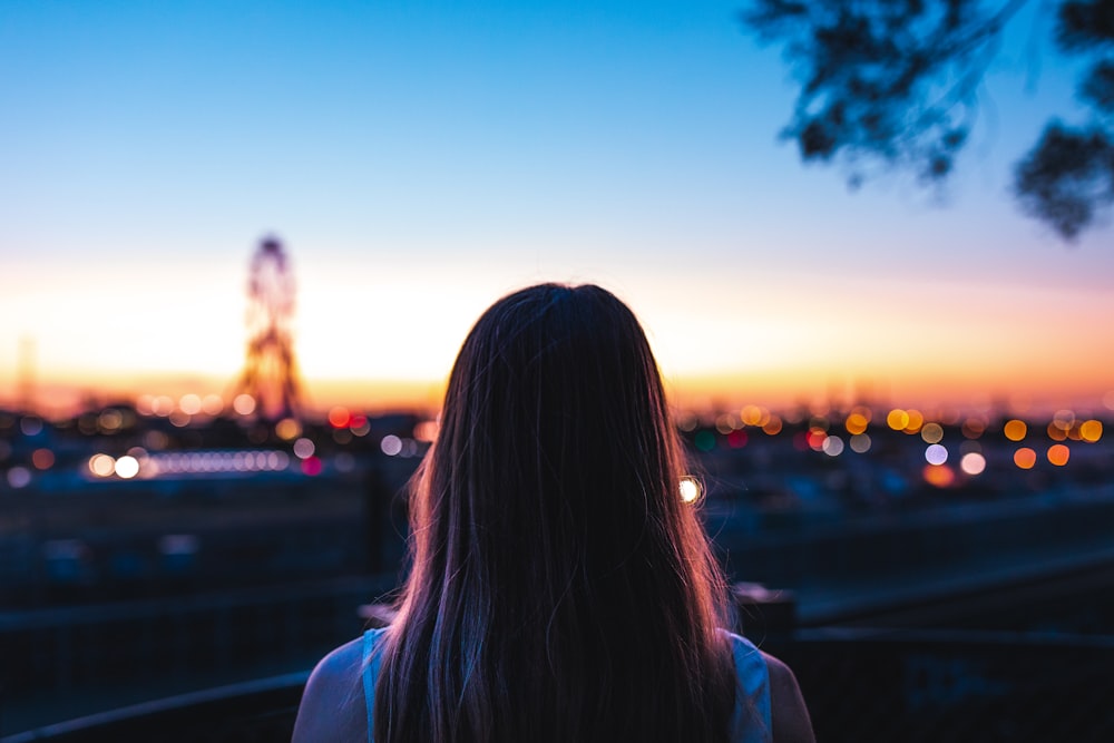 woman in white shirt standing near body of water during sunset