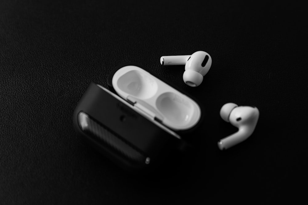 white apple earpods beside black leather case