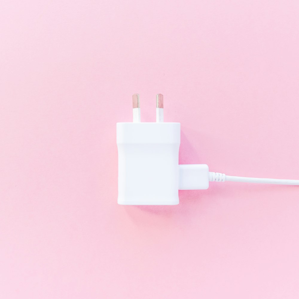 white charger adapter on pink surface