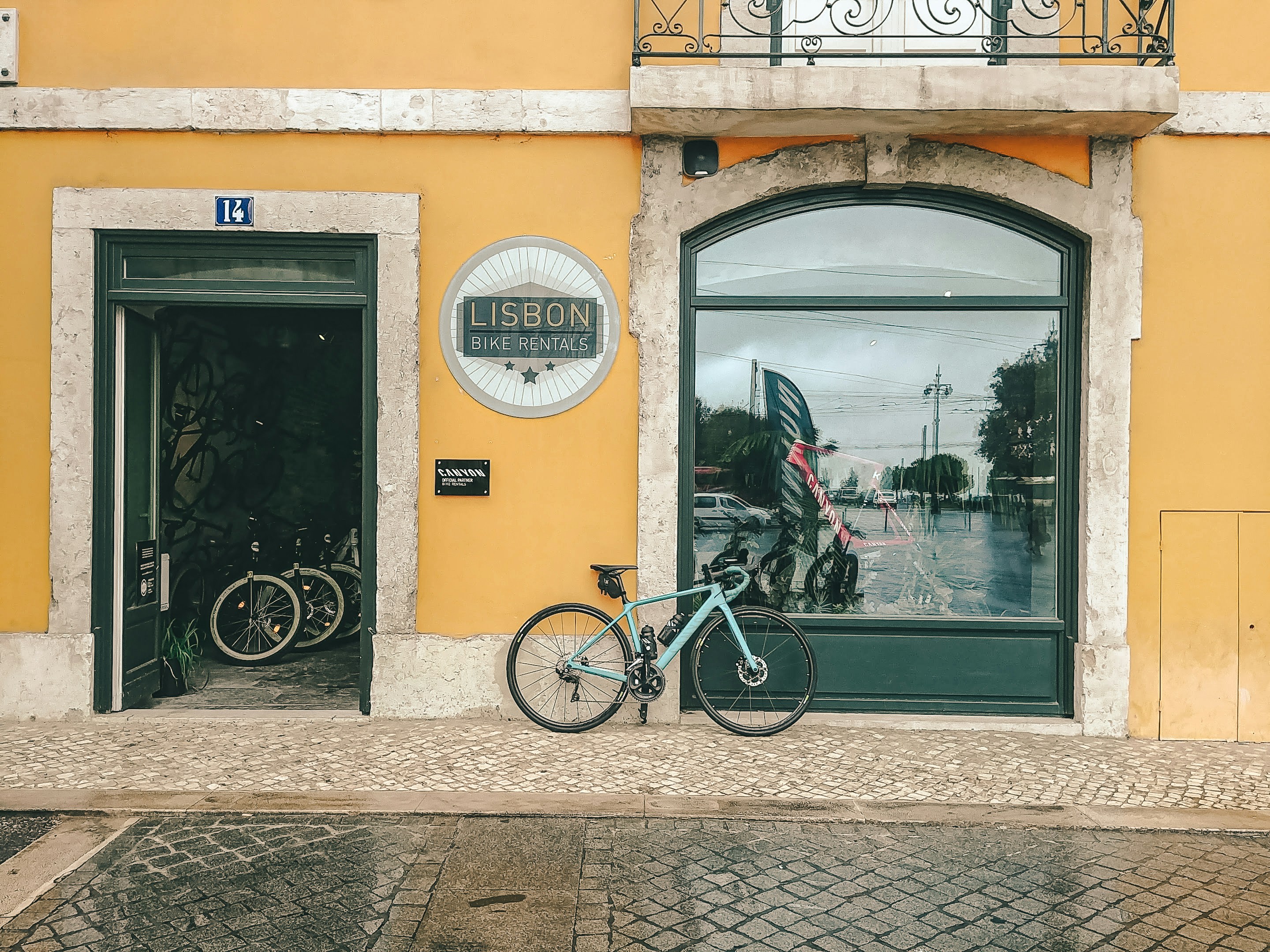 bicicleta preta estacionada ao lado de edifício de concreto marrom durante o dia