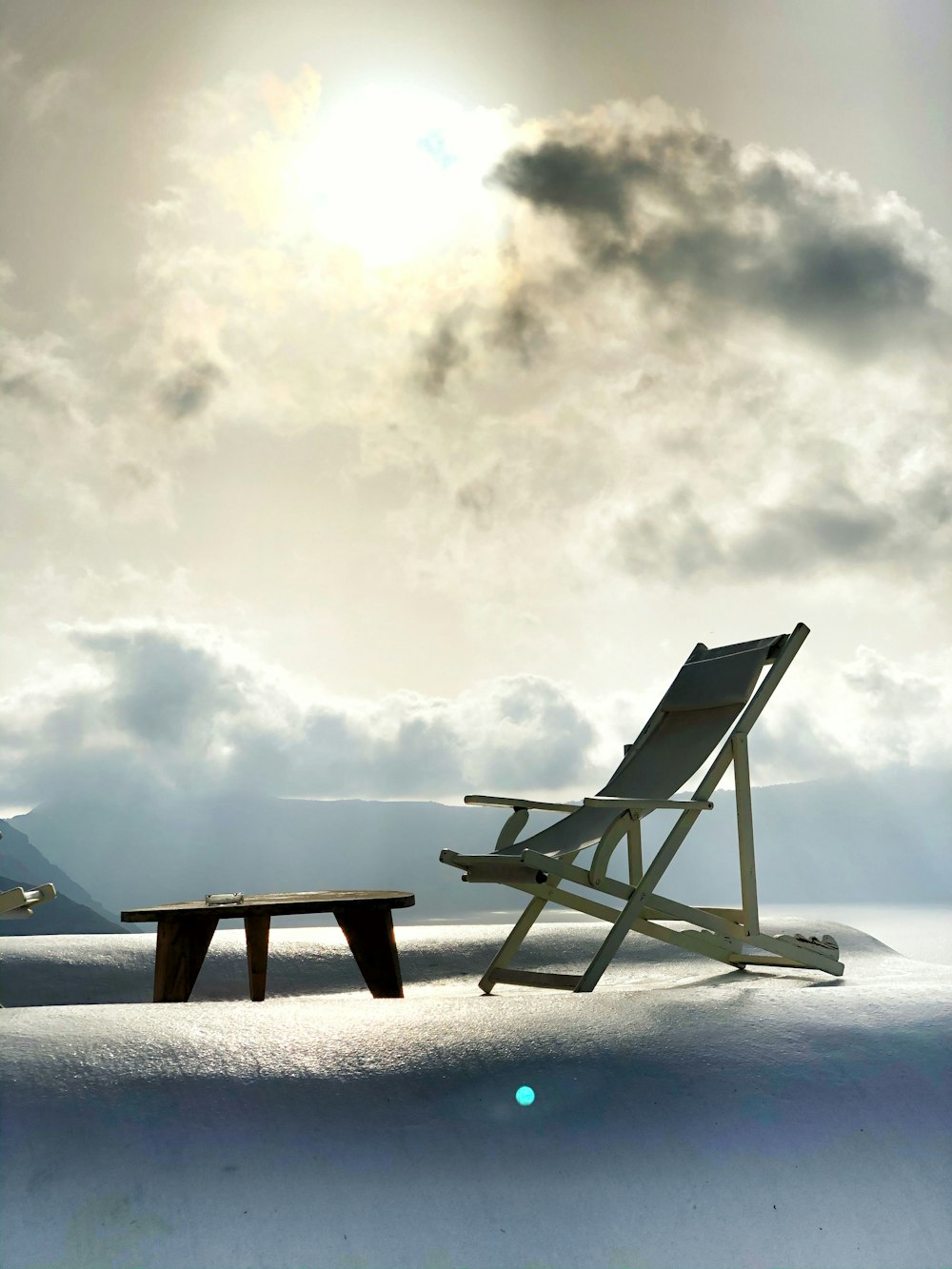 sedia pieghevole in legno marrone su terreno innevato sotto nuvole bianche durante il giorno