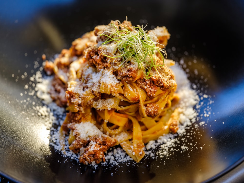 pasta with green leaf on black plate