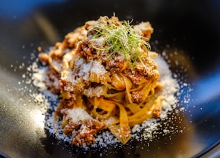 pasta with green leaf on black plate