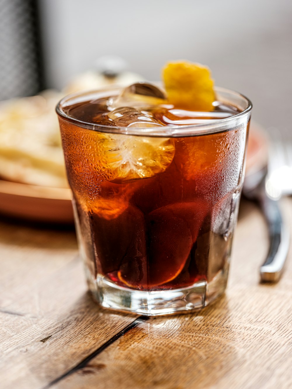 clear drinking glass with brown liquid and ice