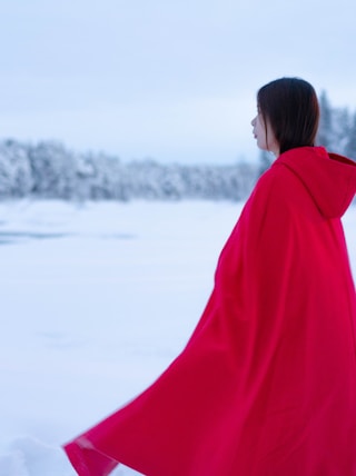 woman in red coat standing on snow covered ground during daytime