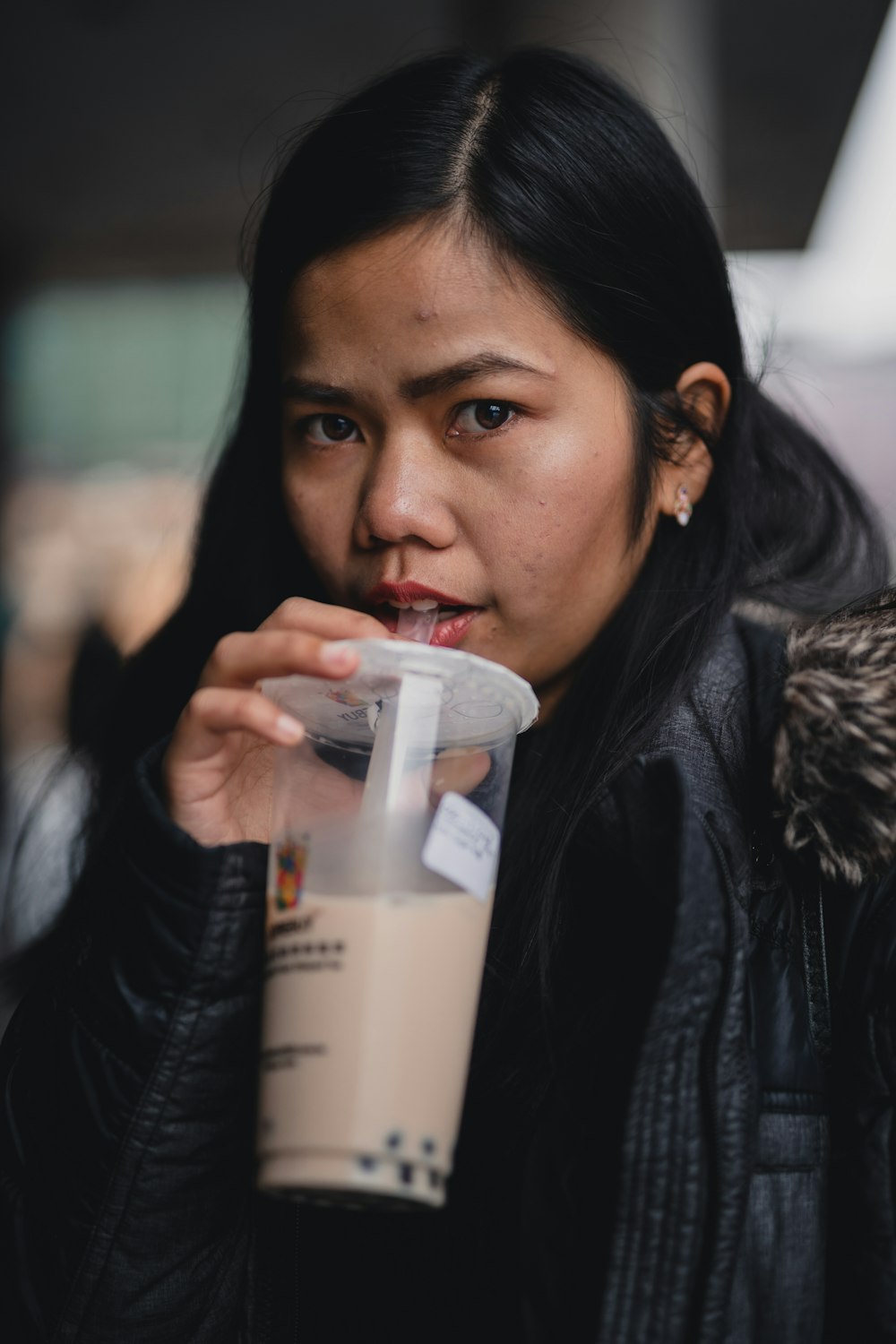 woman in black leather jacket holding white plastic cup