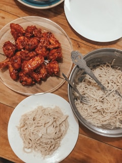 A rustic wooden table set with plates of crispy chicken wings and side dishes.