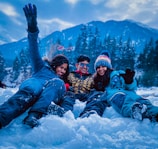3 women lying on snow covered ground during daytime