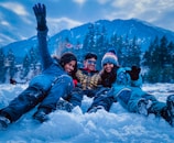 3 women lying on snow covered ground during daytime