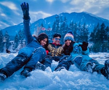 3 women lying on snow covered ground during daytime