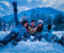 3 women lying on snow covered ground during daytime