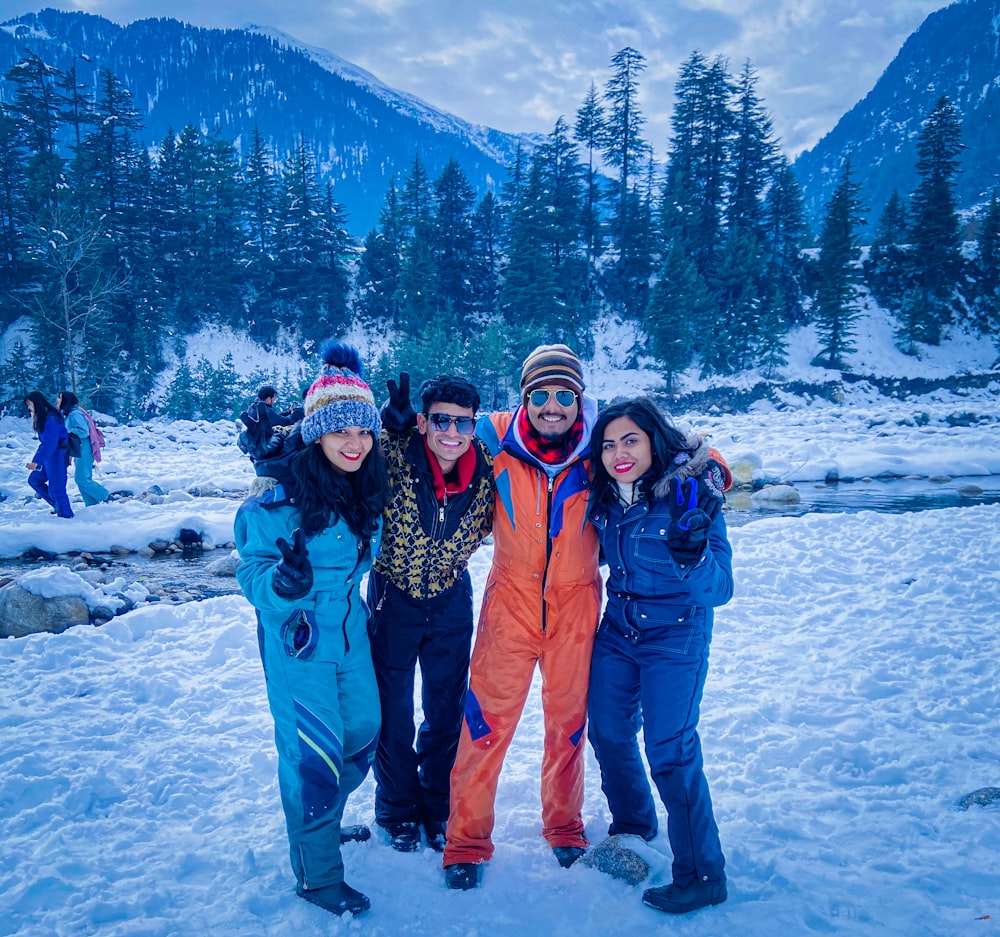 2 mujeres y hombres de pie en el suelo cubierto de nieve durante el día