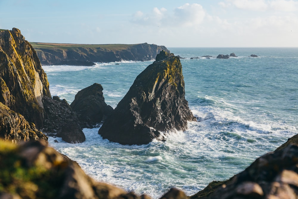 black rock formation on sea under blue sky during daytime