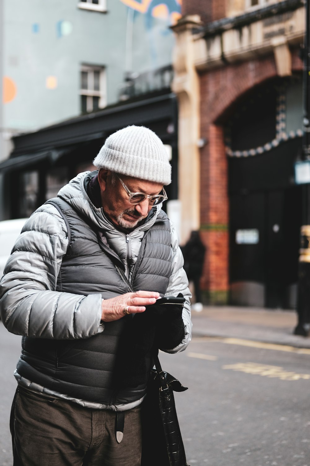 man in gray hoodie and black pants sitting on sidewalk during daytime