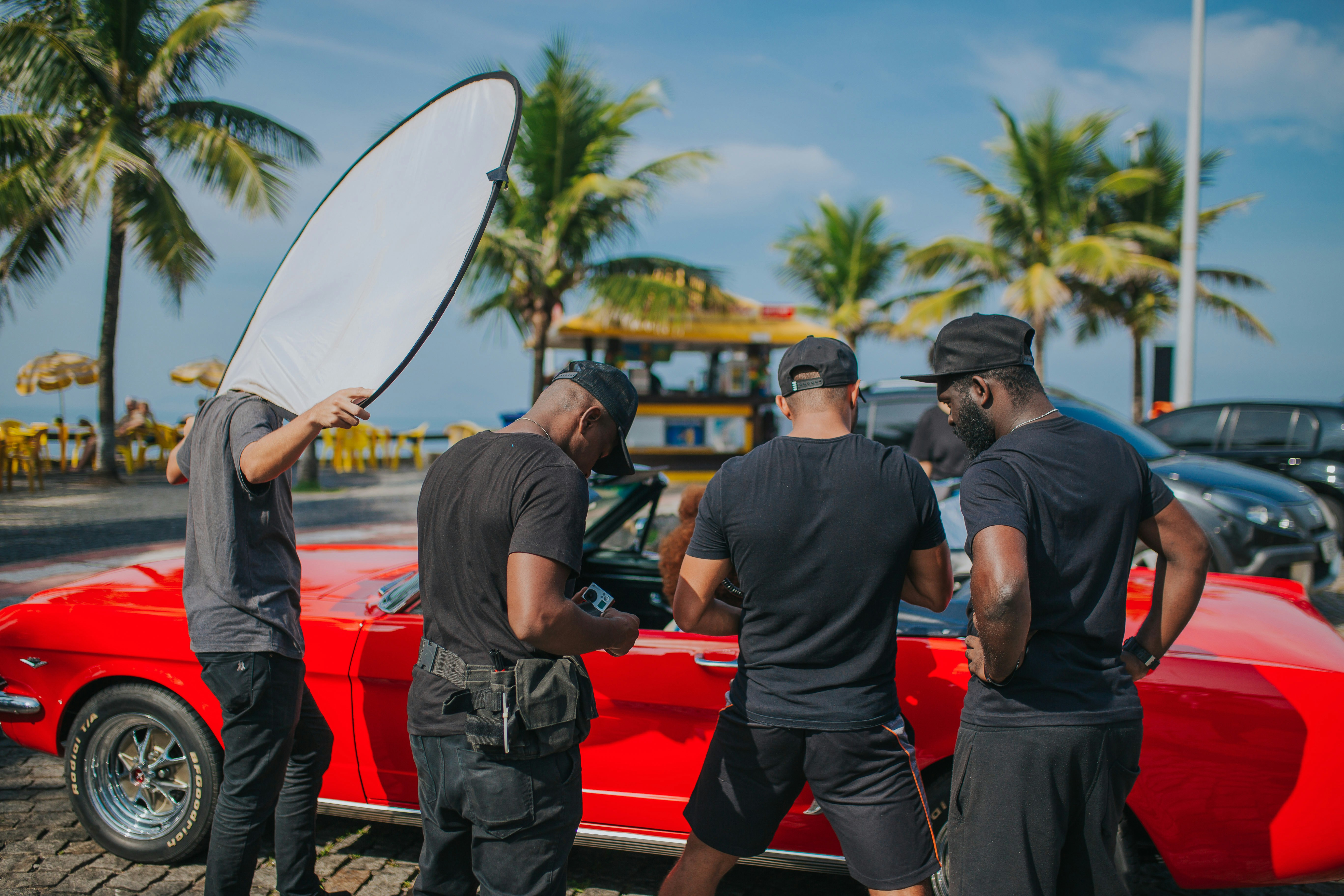 man in black crew neck t-shirt and black pants sitting on red convertible car during