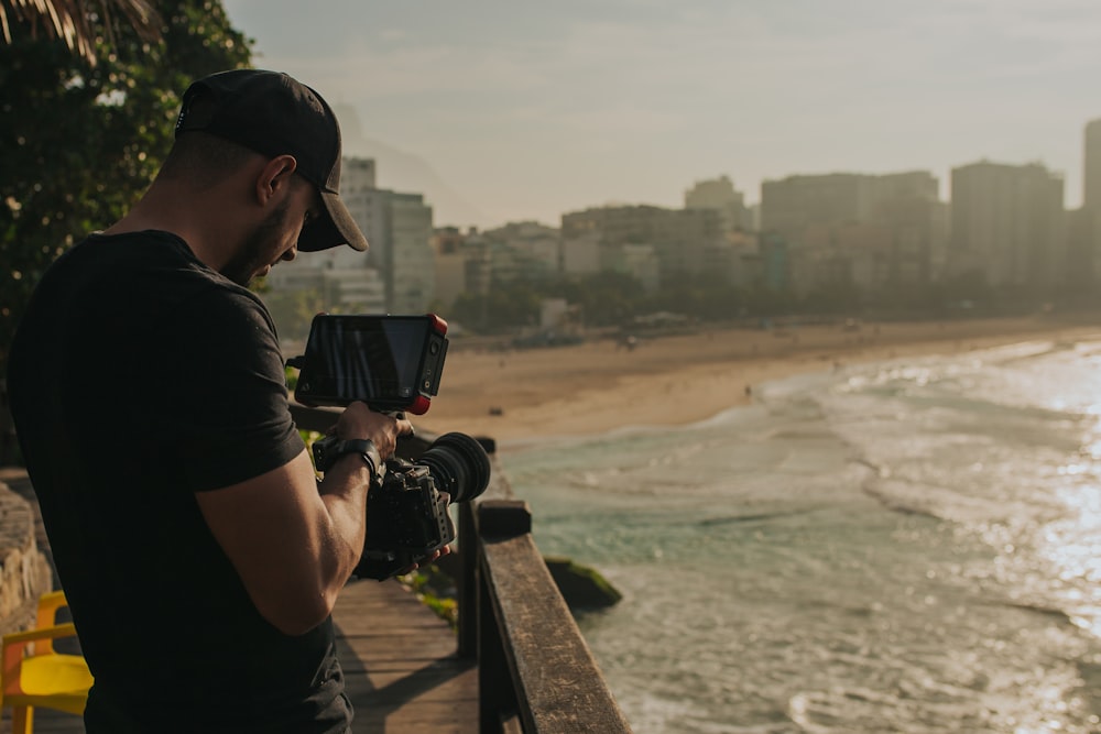 man in black t-shirt holding black dslr camera