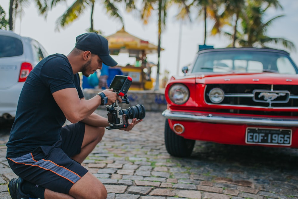 man in black t-shirt and black shorts holding black dslr camera